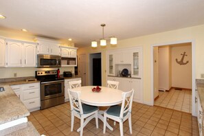 Kitchen features a central island, stainless steel oven, microwave, and toaster, along with a dining table and chairs.