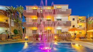 Um hotel com piscina, fonte e área de estar externa.
