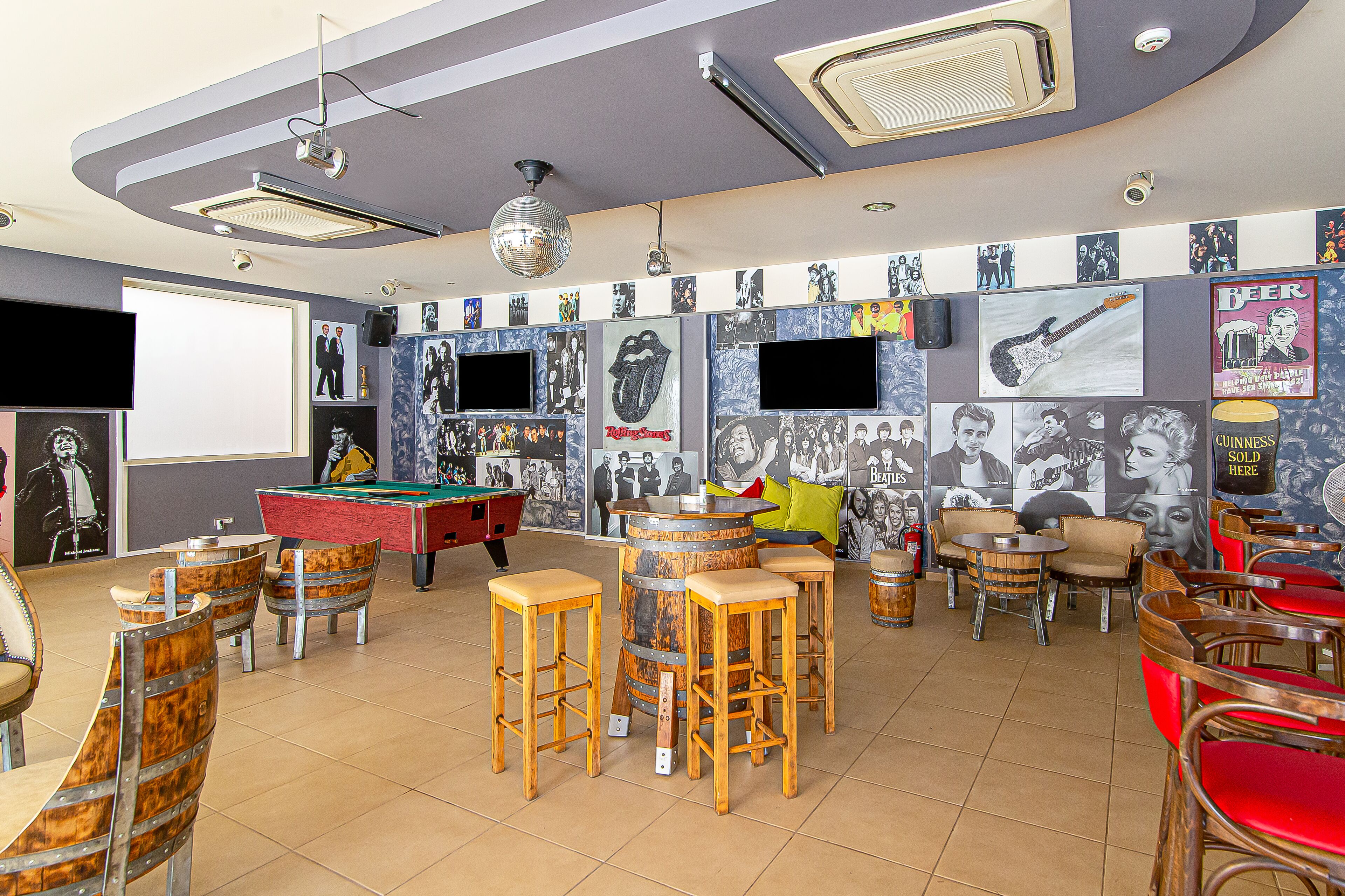 Zona de bar con mesas de billar, taburetes y un jukebox.