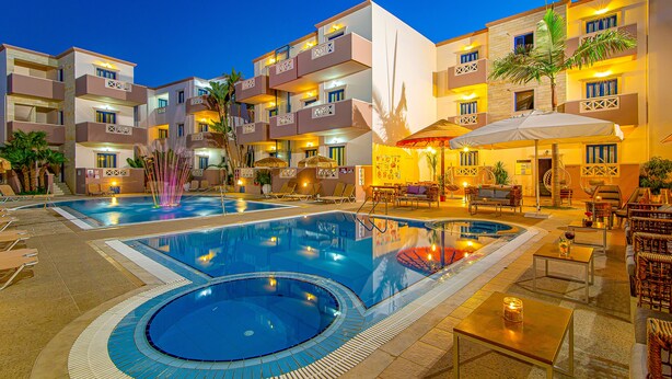 Um hotel com várias piscinas, áreas de estar ao ar livre e fachada bem iluminada.