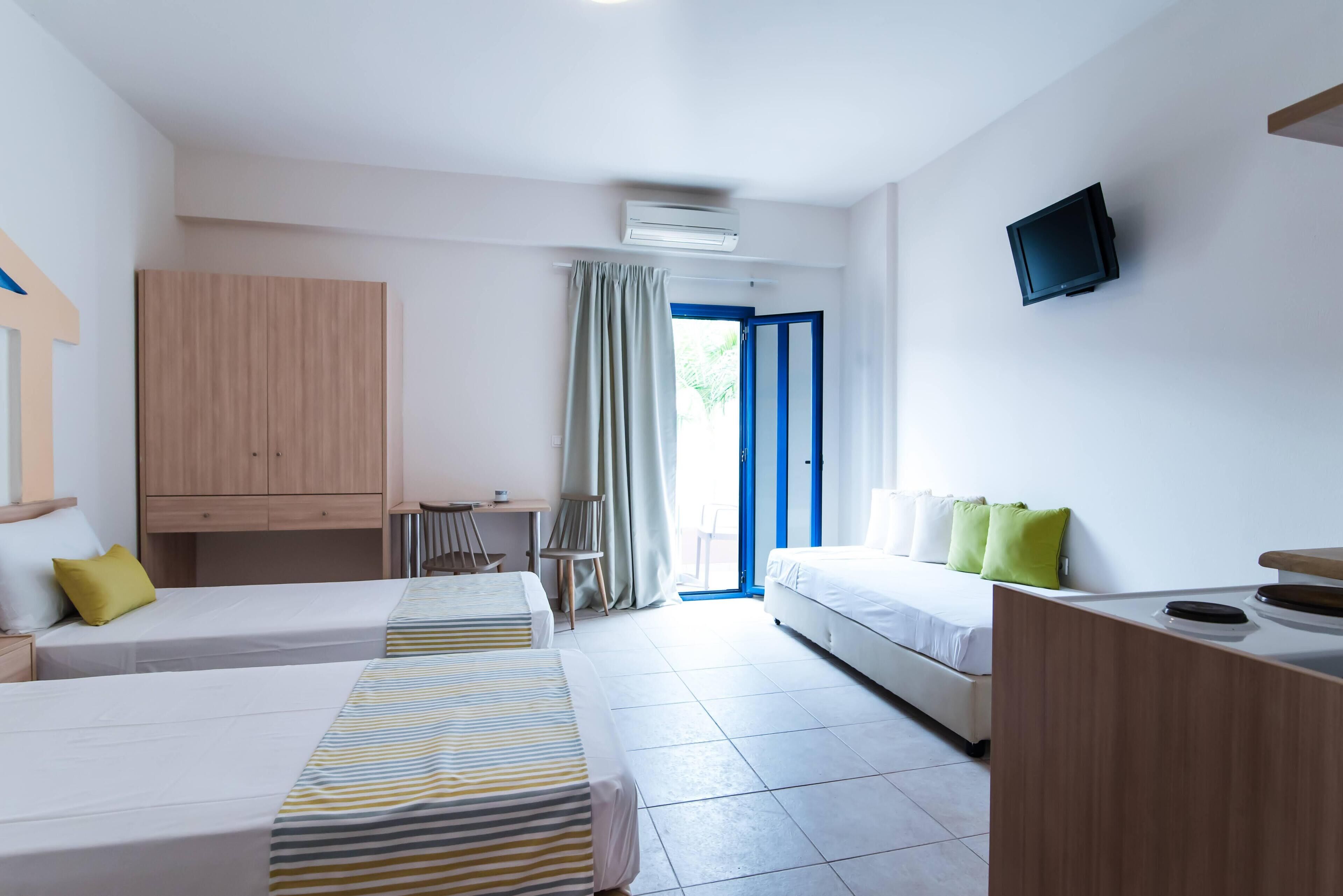 A hotel room with two beds, a desk, a chair, a TV, and a wardrobe.