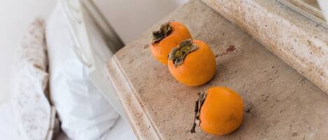 Three persimmons on a textured surface, possibly a table or countertop, with a white pillow and a mirror in the background.