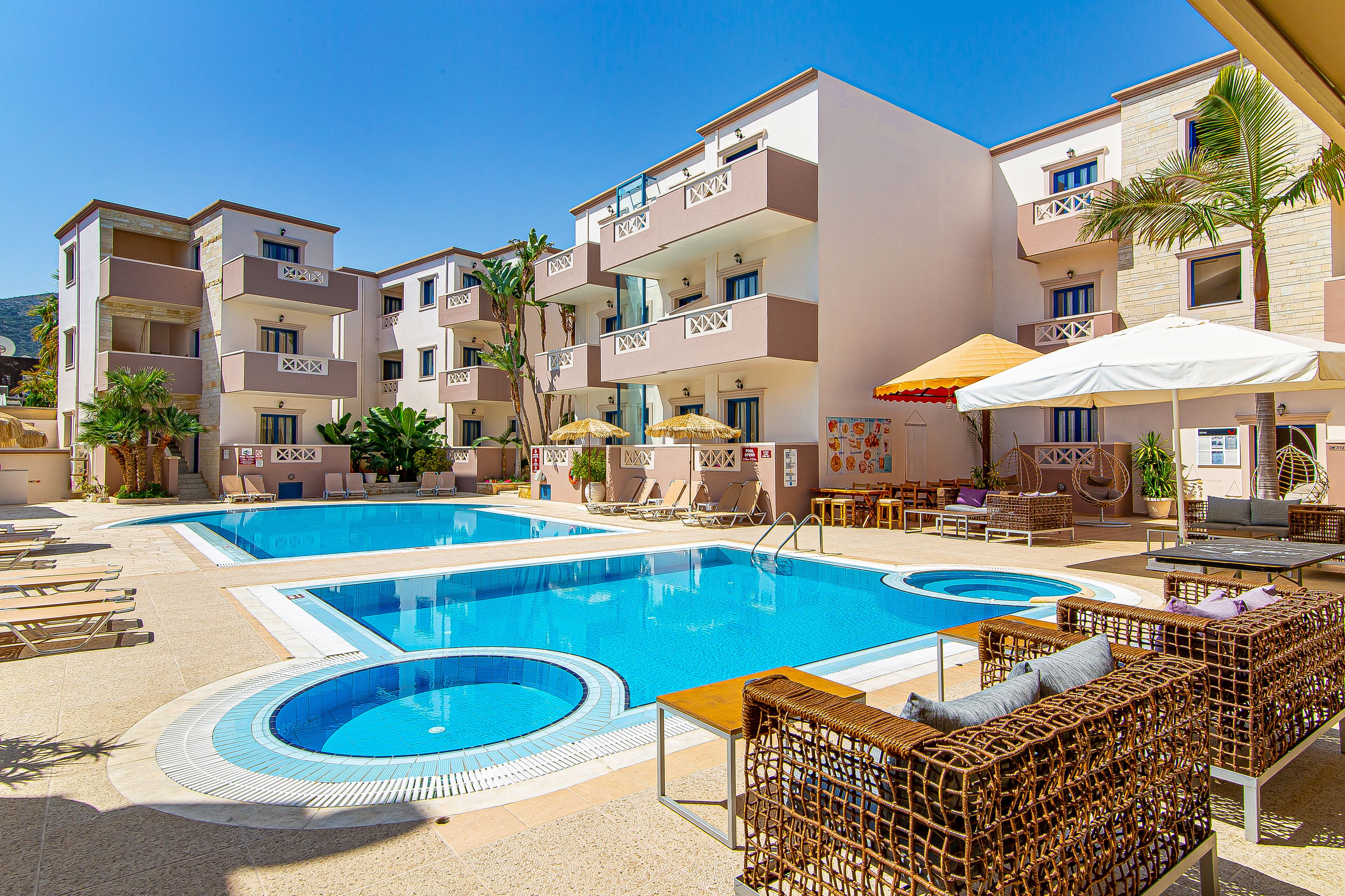 Un hotel con piscina, sillones de descanso y zonas de estar al aire libre.