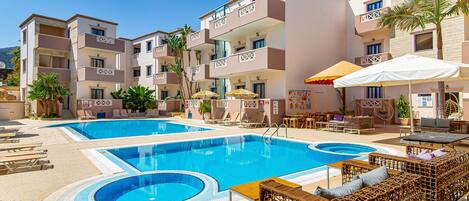 Un hotel con piscina, sillones de descanso y zonas de estar al aire libre.