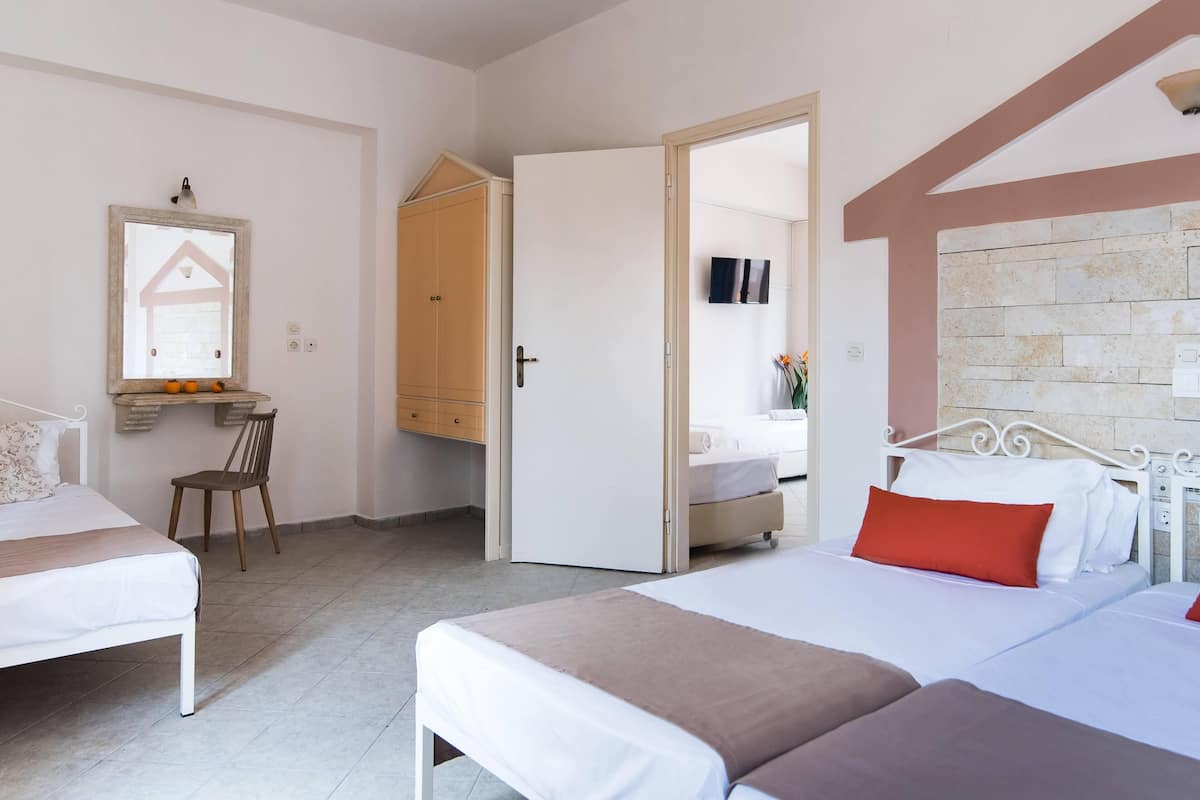 A hotel room with two beds, a desk, a chair, and a wardrobe.