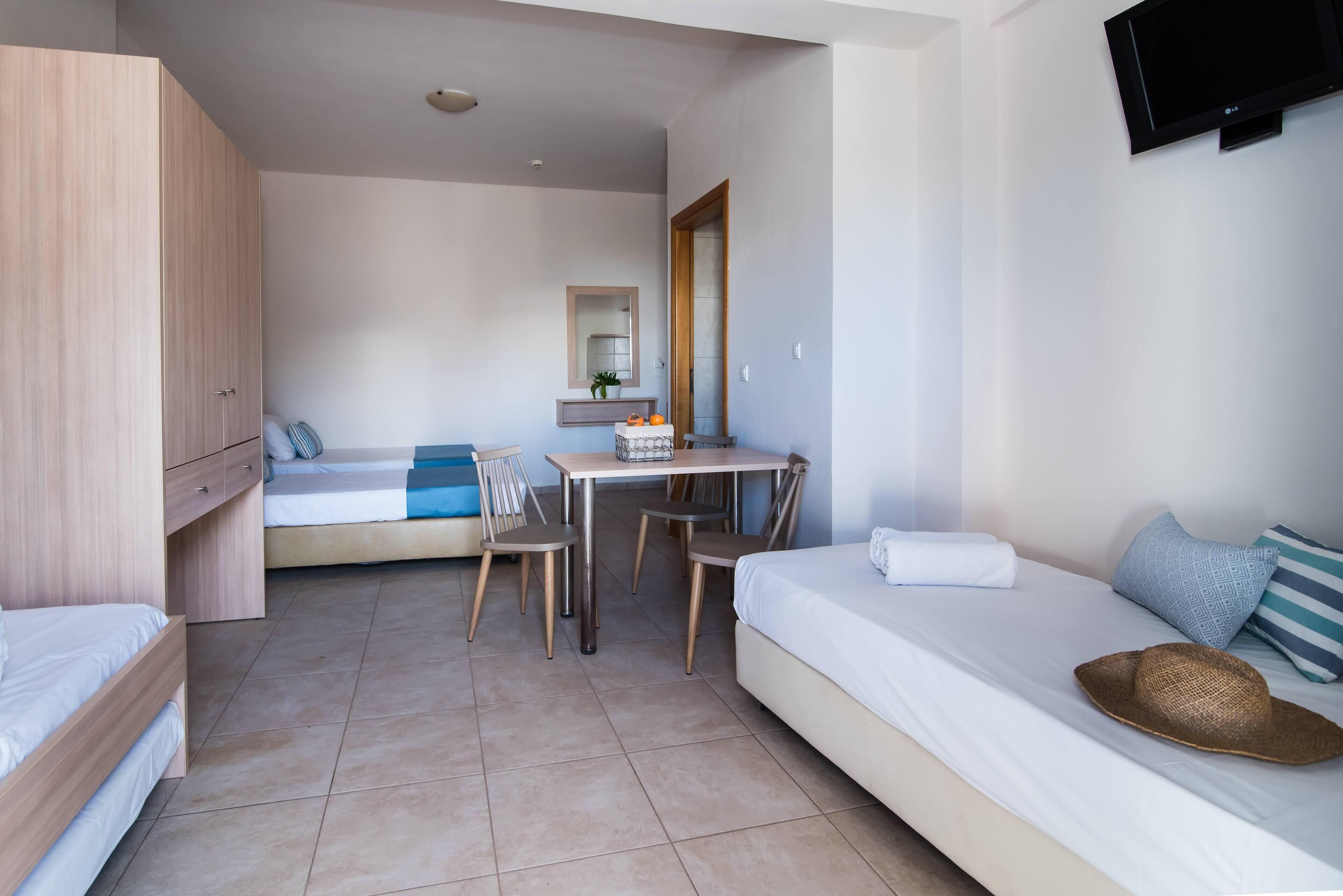 A bedroom with a bed, a desk, and a TV.