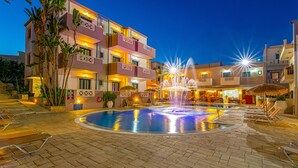 Hotel com piscina, espreguiçadeiras e uma fonte.