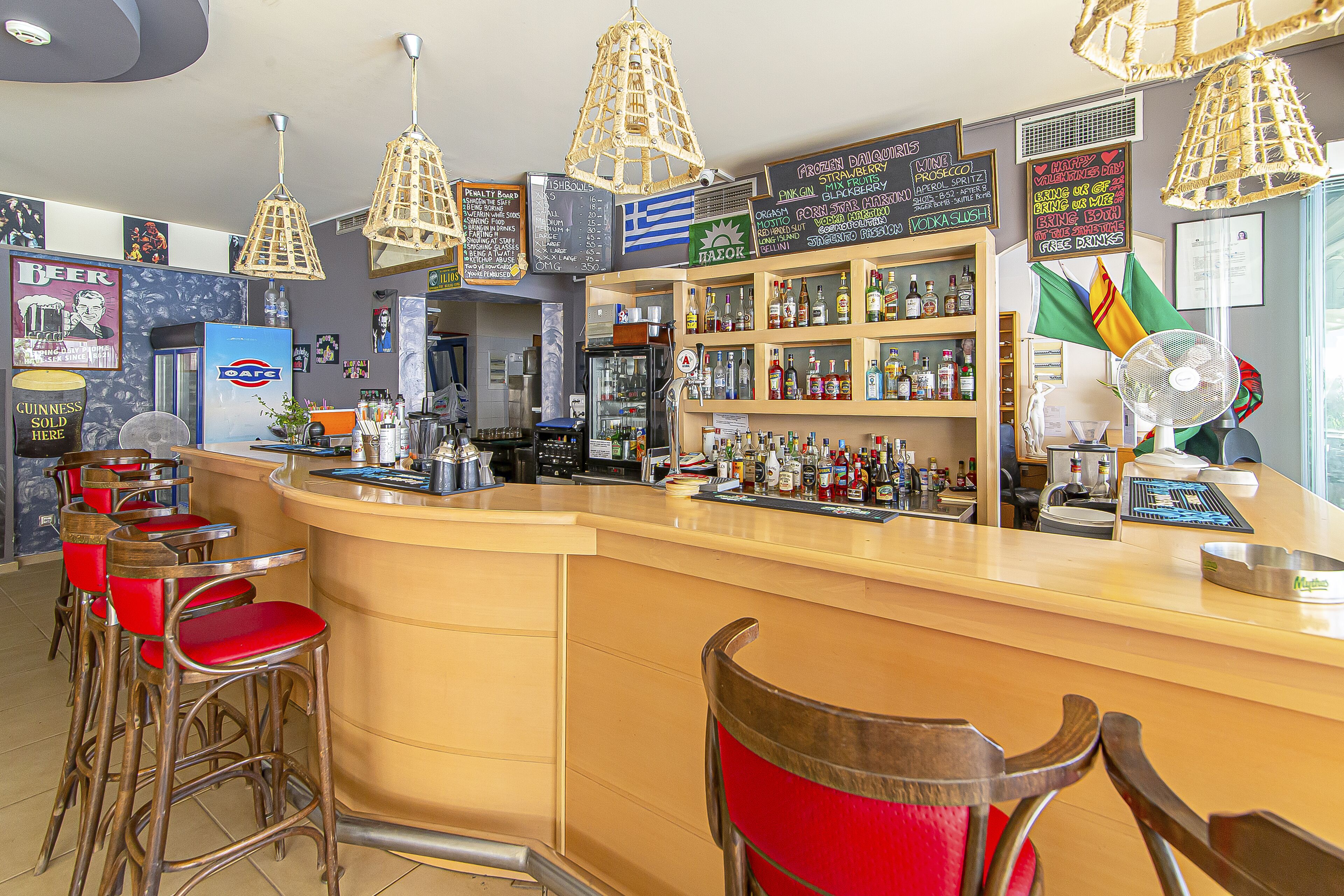 A bar with a counter, stools, and various bottles.