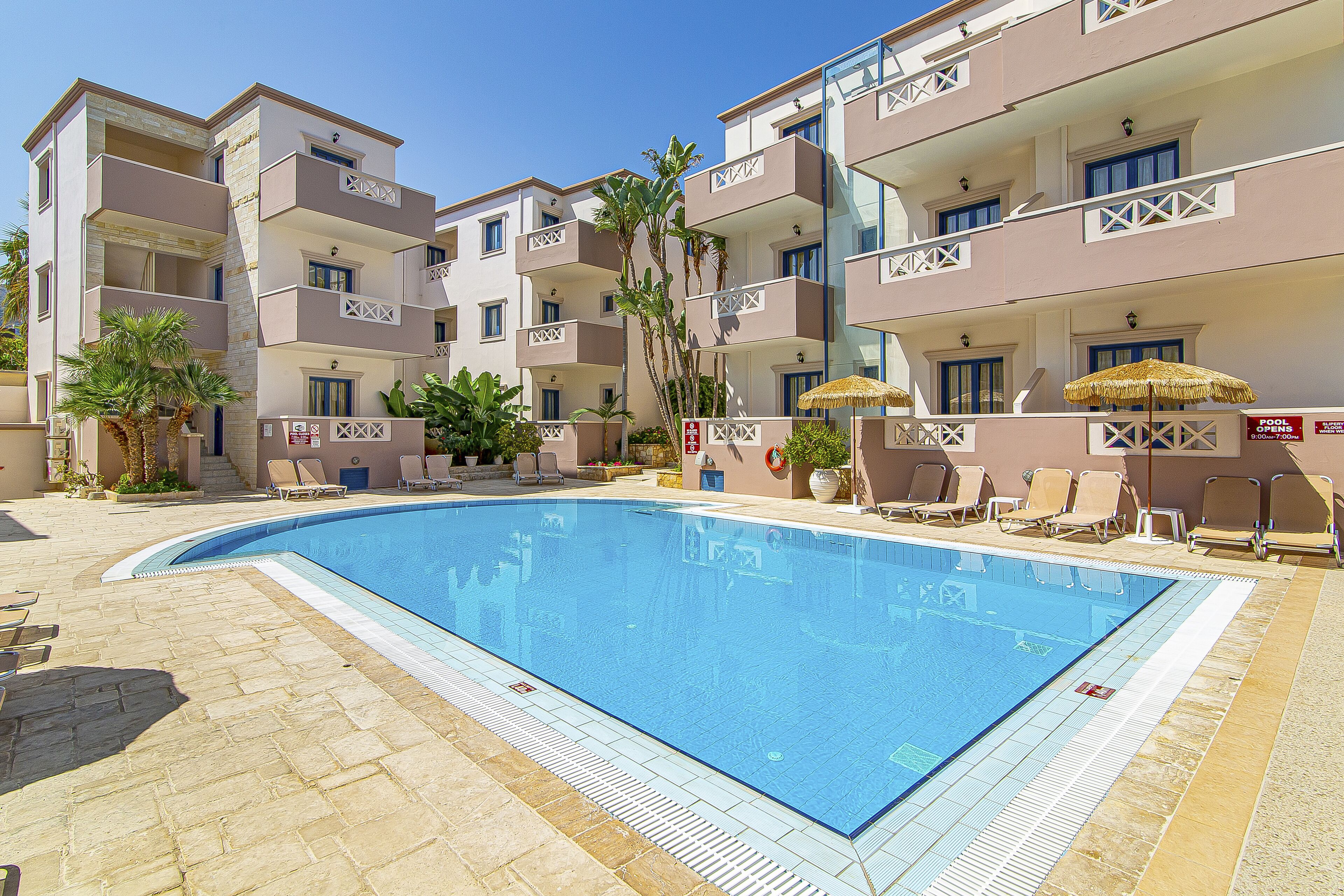 A swimming pool surrounded by lounge chairs and a building with balconies.