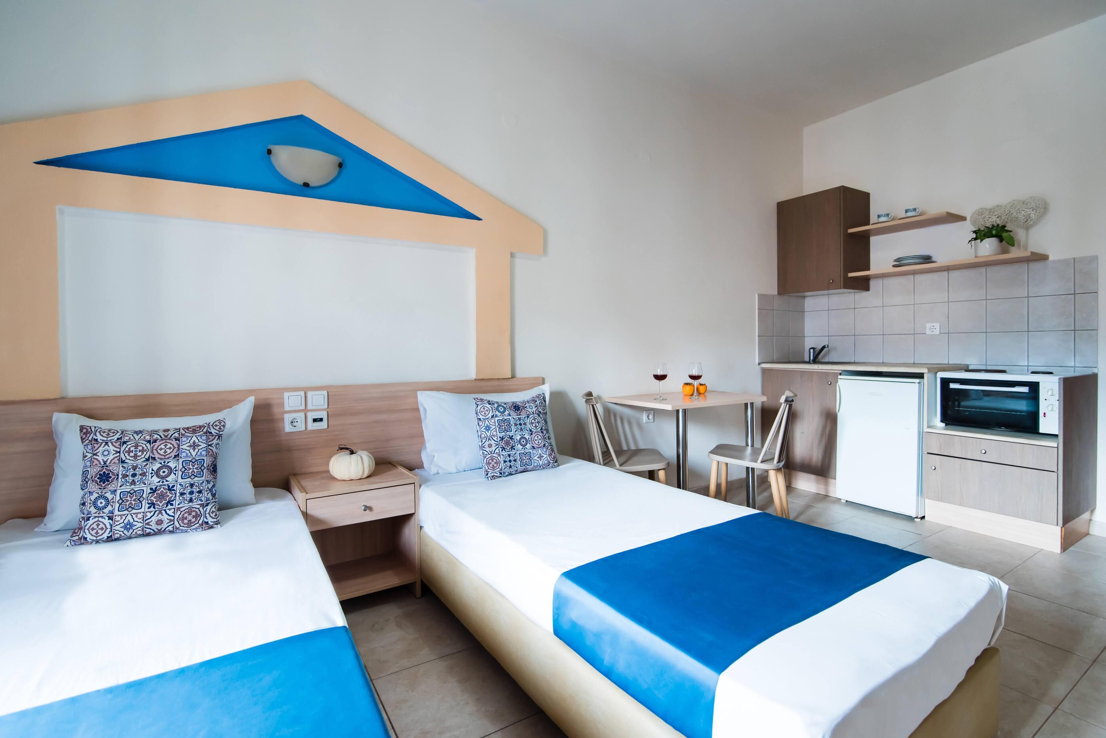Une chambre d’hôtel avec deux lits, une kitchenette, un petit coin repas et une salle de bain.
