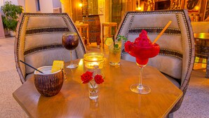 Mesa posta com bebidas, uma vela e um vaso de rosas vermelhas.
