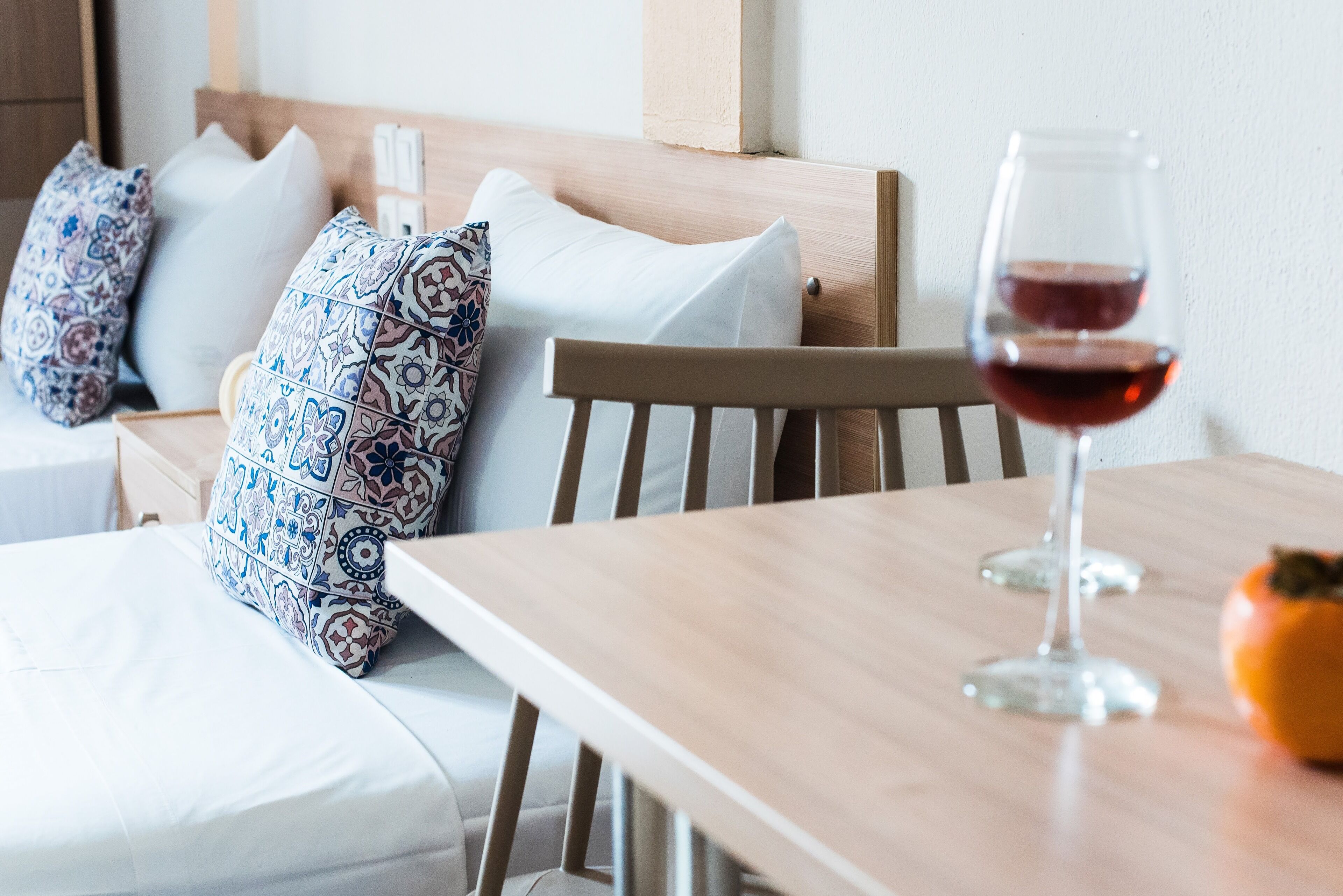 Een houten eettafel met een glas rode wijn en een granaatappel.