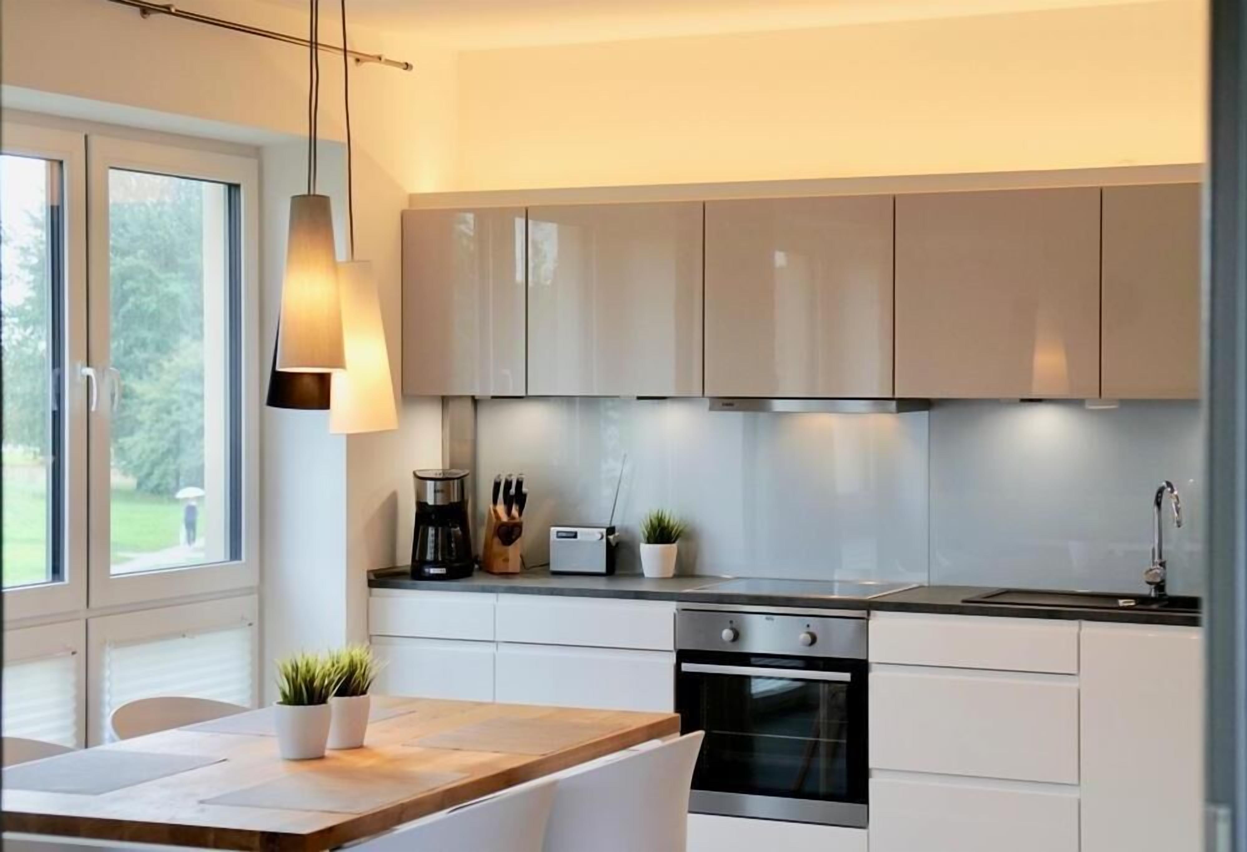 Une cuisine moderne avec des armoires blanches, un four en acier inoxydable et un plan de travail en bois.