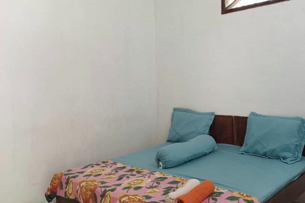 A single bed with a floral bedspread and two blue pillows.
