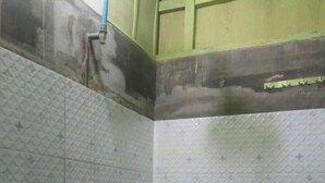Um banheiro pequeno com vaso sanitário, uma lixeira verde e azulejos estampados nas paredes e no chão.