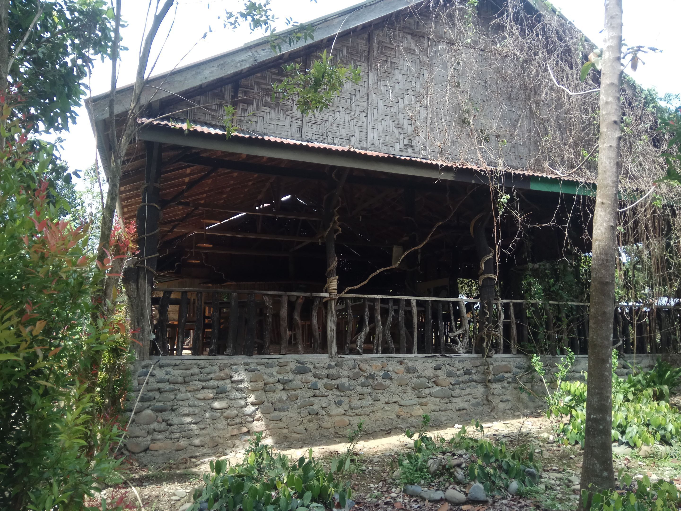 Un edificio rústico con base de piedra, vigas de madera y techo de metal.