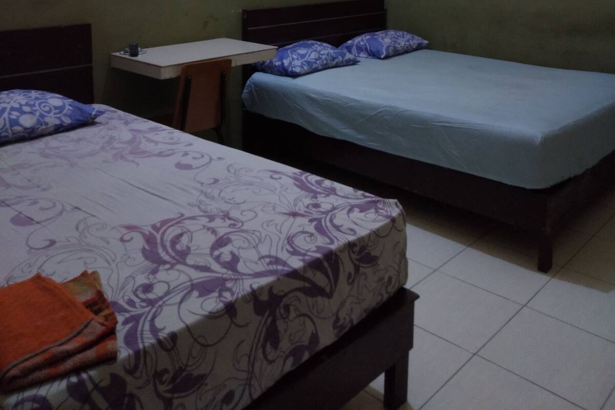 A room with two beds, a small table, and a chair.