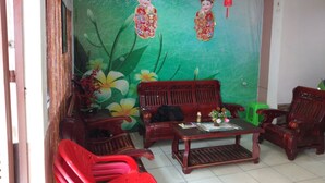 A traditional living room with a green wall, two wooden sofas, a coffee table, and a red plastic chair.