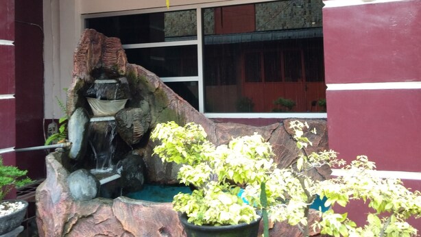 A rock garden with a water feature, potted plants, and a red lantern.