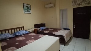 A bedroom with two beds, a wall-mounted air conditioner, a door, and a small table.