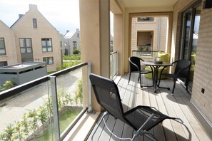 A balcony with a table and chairs, a glass railing, and a view of neighboring buildings. - Hello and welcome to Apartment Friesland 4! (Dangast)