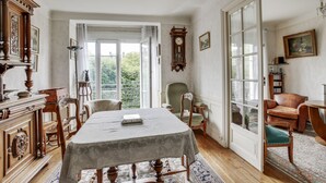 Quarto tradicional com uma mesa de jantar, cadeiras, um relógio e vista para o verde lá fora.