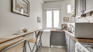 Uma cozinha compacta com geladeira, micro-ondas, forno e pia.