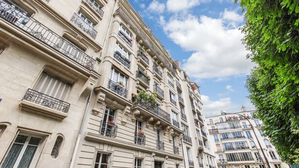 Um edifício de vários andares com varandas, janelas amplas e céu claro.