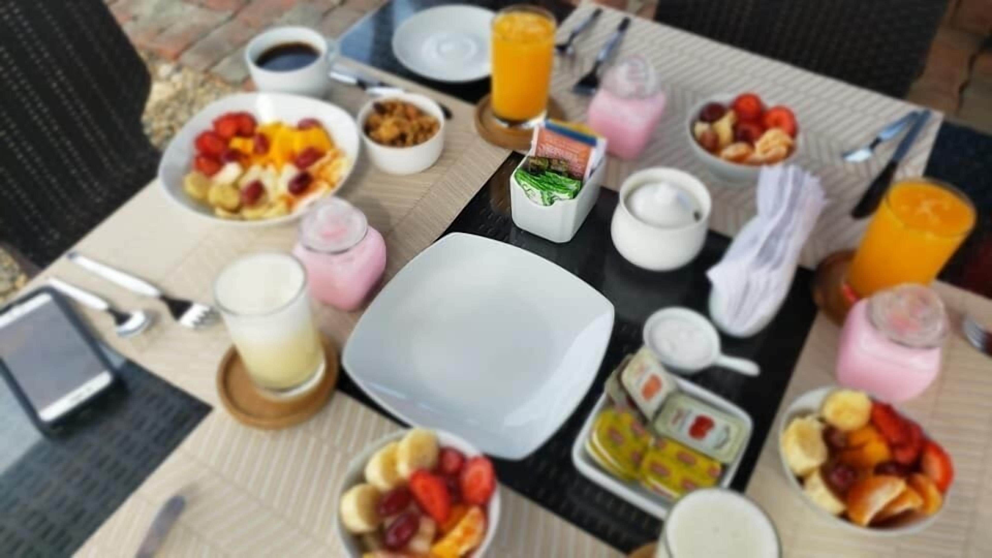 A breakfast table with various food items, drinks, and a smartphone.
