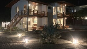 A two-story house with a balcony, a staircase, and a well-lit outdoor area with plants and lanterns. - El Samay Hotel Boutique (Canoas de Punta Sal)
