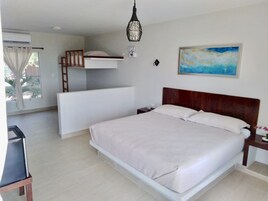 A bedroom with a bunk bed, a single bed, a bedside table, a lamp, and a painting on the wall.