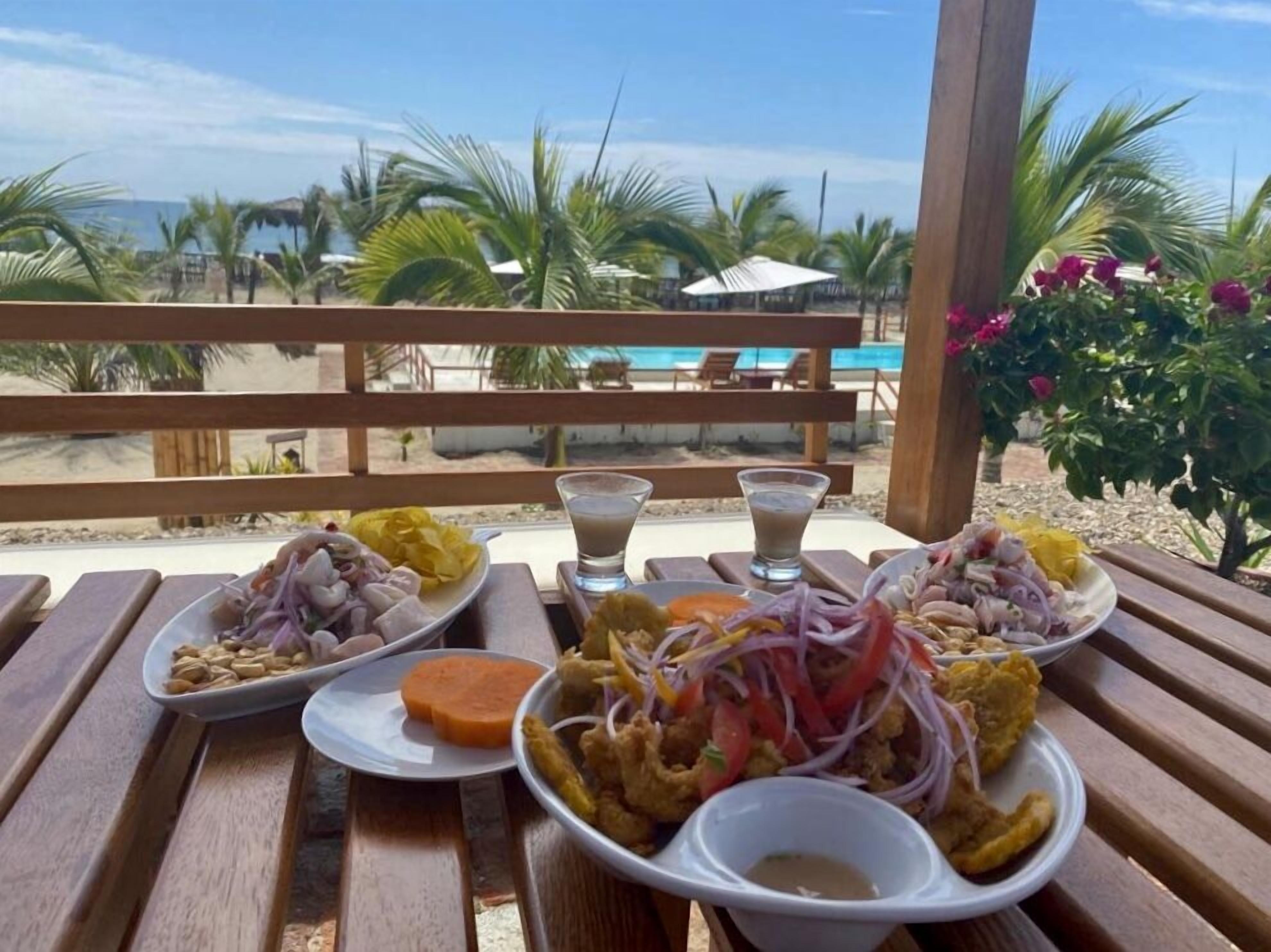 A table with various dishes, a pool, and palm trees in the background.