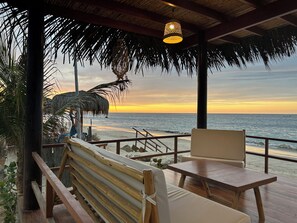 A beachside seating area with a wooden bench and table, overlooking the ocean at sunset. - El Samay Hotel Boutique (Canoas de Punta Sal)