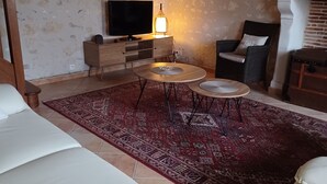 Ein Wohnzimmer mit Sofa, Couchtisch, Fernseher und Kamin.