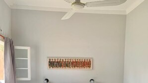 Una camera da letto con un letto, una ventola a soffitto, un'opera d'arte a parete, comodini e una finestra con tende.
