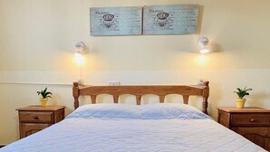 Un letto con struttura e testiera in legno, affiancato da comodini con lampade e piante in vaso.