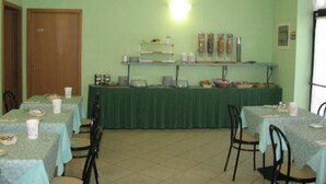 A dining area with tables set for meals, a buffet counter with food items, and a door on the left. - Albergo Elena (Pianoro)