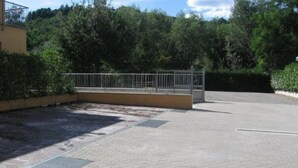 A paved parking area with a metal gate and a building in the background. - Albergo Elena (Pianoro)