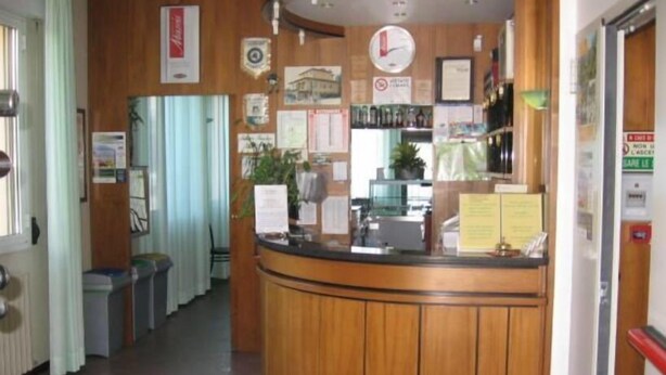 A reception desk with a clock, framed pictures, and a bulletin board. - Albergo Elena (Pianoro)