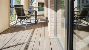 Ein Balkon mit Tisch und Stühlen, einer Glastür und Blick auf Gebäude.
