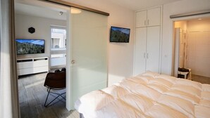Ein Schlafzimmer mit einem Bett, einem Fernseher, einem Kleiderschrank und einem Sessel.