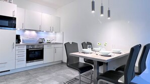 A modern kitchen with white cabinets, a built-in oven, and a dining area with a table and chairs. - Hello and welcome to the "Lighthouse" (Dangast)
