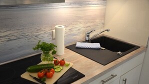A kitchen with a modern design, featuring a black countertop, a sink, and a cutting board with vegetables. - Hello and welcome to the "Lighthouse" (Dangast)