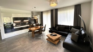 Een moderne woonruimte met een keuken, eethoek en een zwarte leren bank.