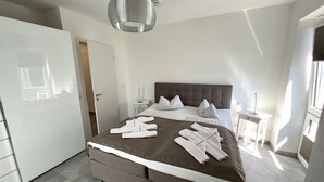 Een moderne hotelkamer met een groot bed, een nachtkastje, een kledingkast en een hanglamp.