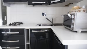 Een moderne keuken met zwarte kastjes, een wit aanrecht, een gasfornuis, een spoelbak en een ingebouwde oven.