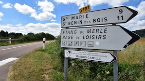 En vejskilte med flere destinationer og en mindeplade.