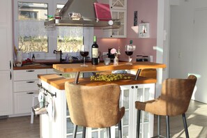 A kitchen with a central island, bar stools, and a wine bottle.
