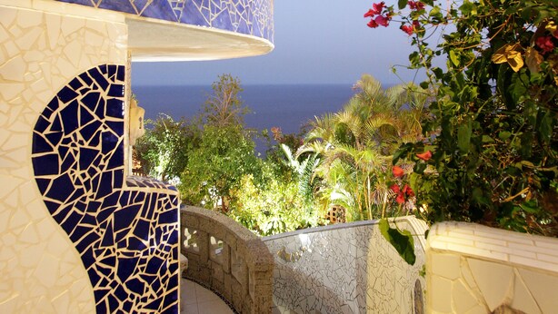 Un bâtiment moderne orné d’une mosaïque, doté d’un escalier en pierre et offrant une vue sur la mer.