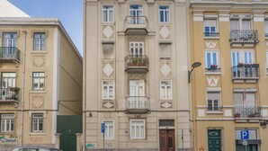 Un edificio de varios pisos con balcones, una puerta verde y un letrero azul de estacionamiento.